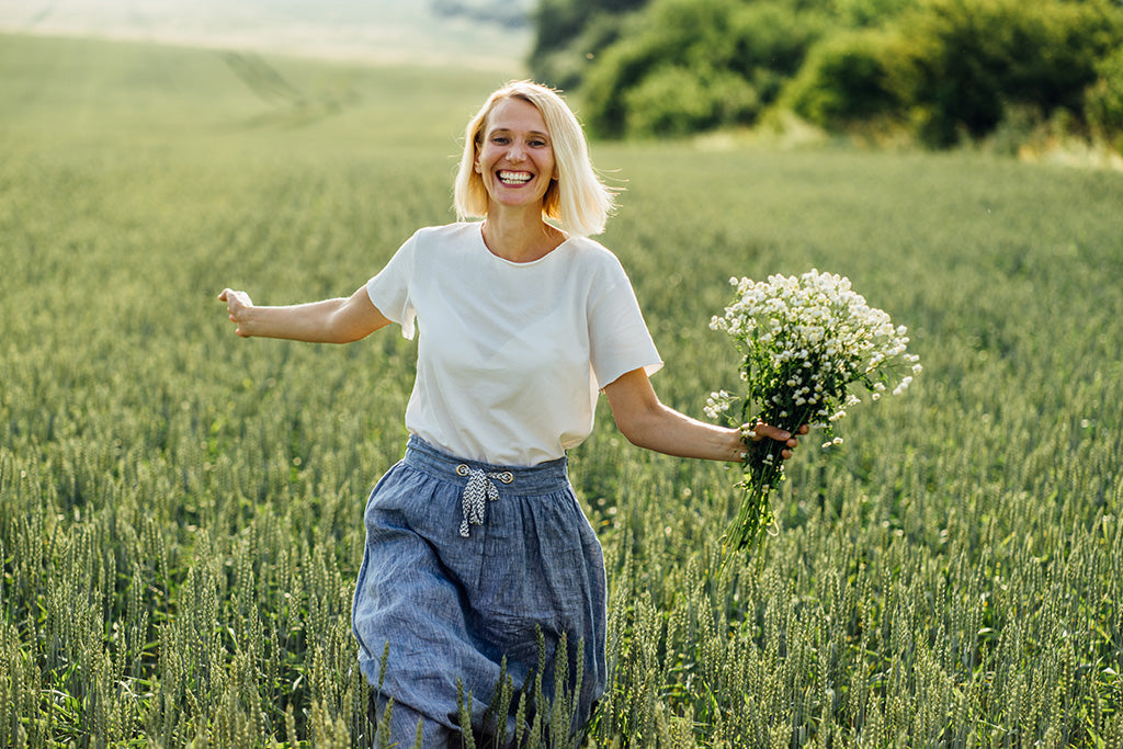Woman_in_white_blouse_and_blue_European_linen_skirt_walking_in_wheat_field