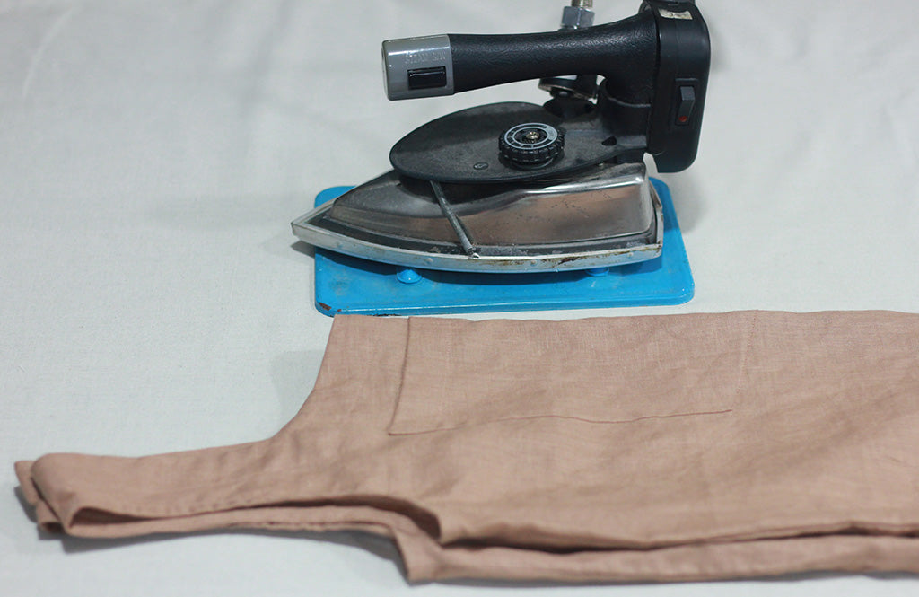 Iron pressing a folded linen dress