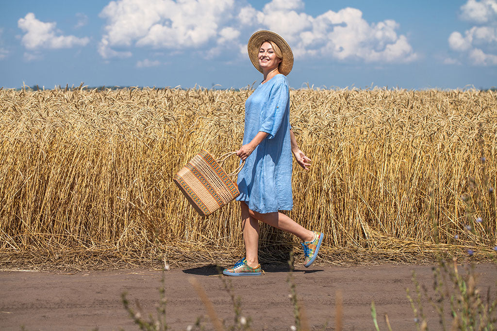 Women in blue linen dress walking past a farm