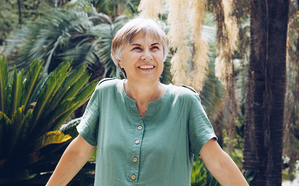 Confident older woman smiling outdoors in a green summer top
