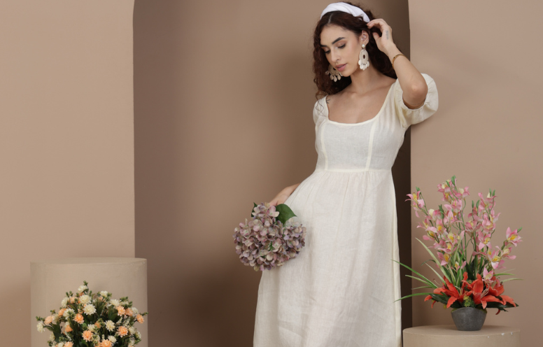 Elegant women’s linen dress styled with flowers in a soft neutral setting