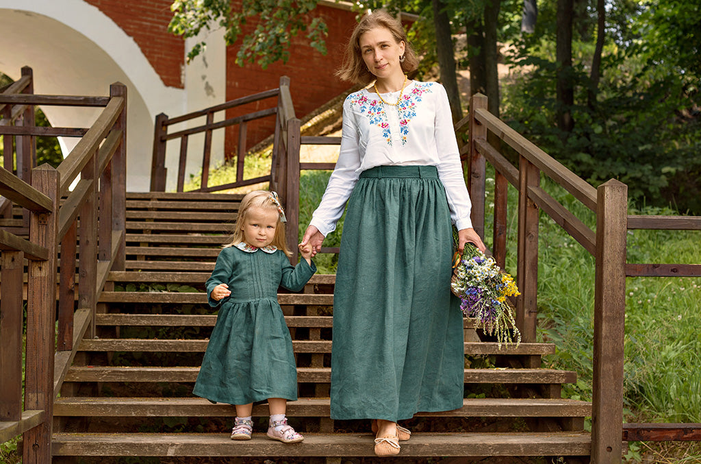 Woman and little girl in linen outfits walking down wooden stairs