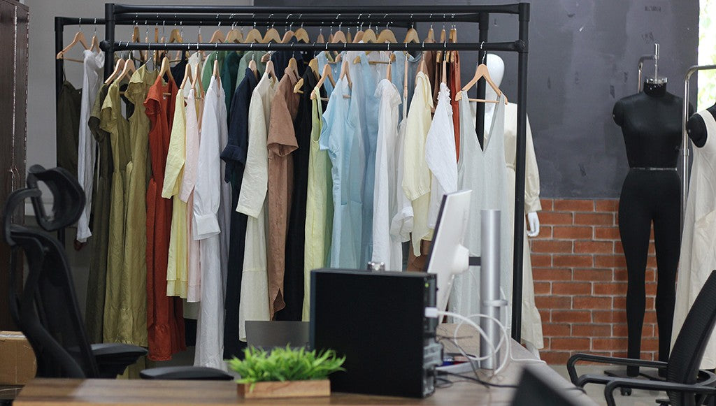 Kuttons fashion design studio workspace with a desk in the foreground and a clothing rack