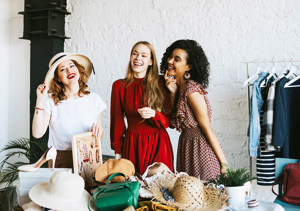Three women smiling while choosing outfits