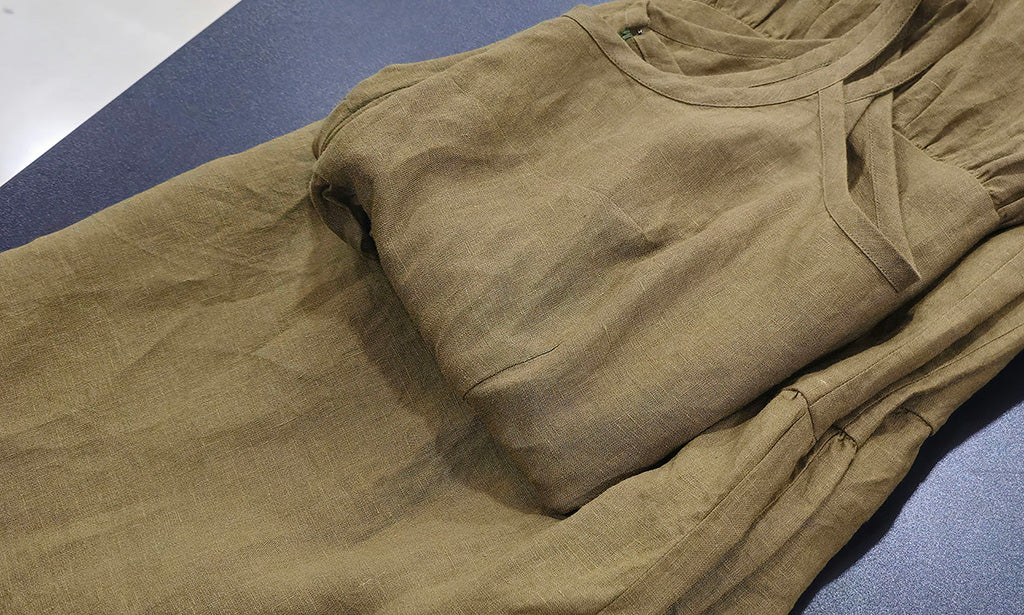 Olive green linen dress folded neatly on table surface