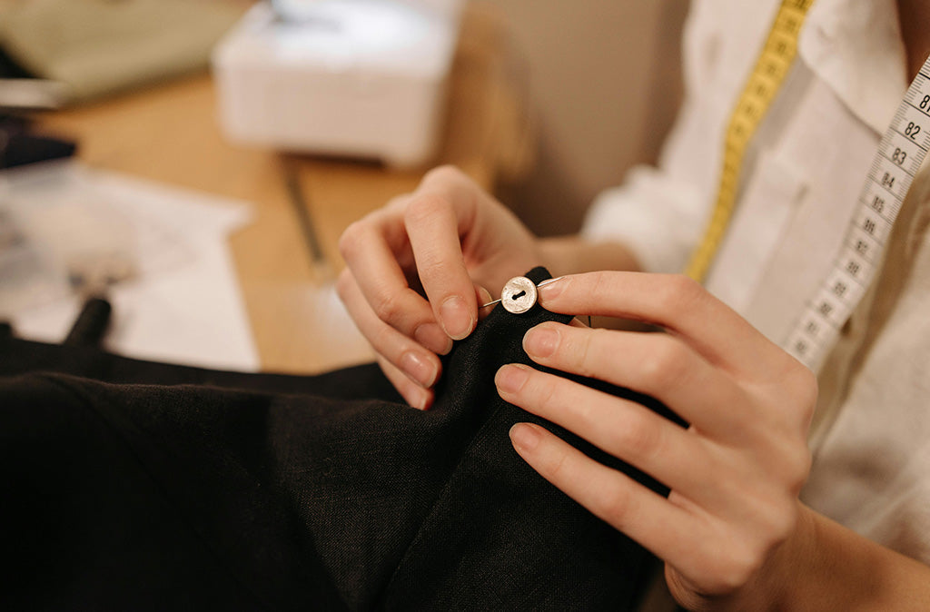 Close-up of hands repairing a garment by sewing a button