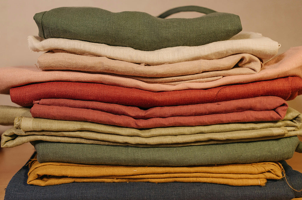 Stack of folded natural linen fabrics in earthy shades