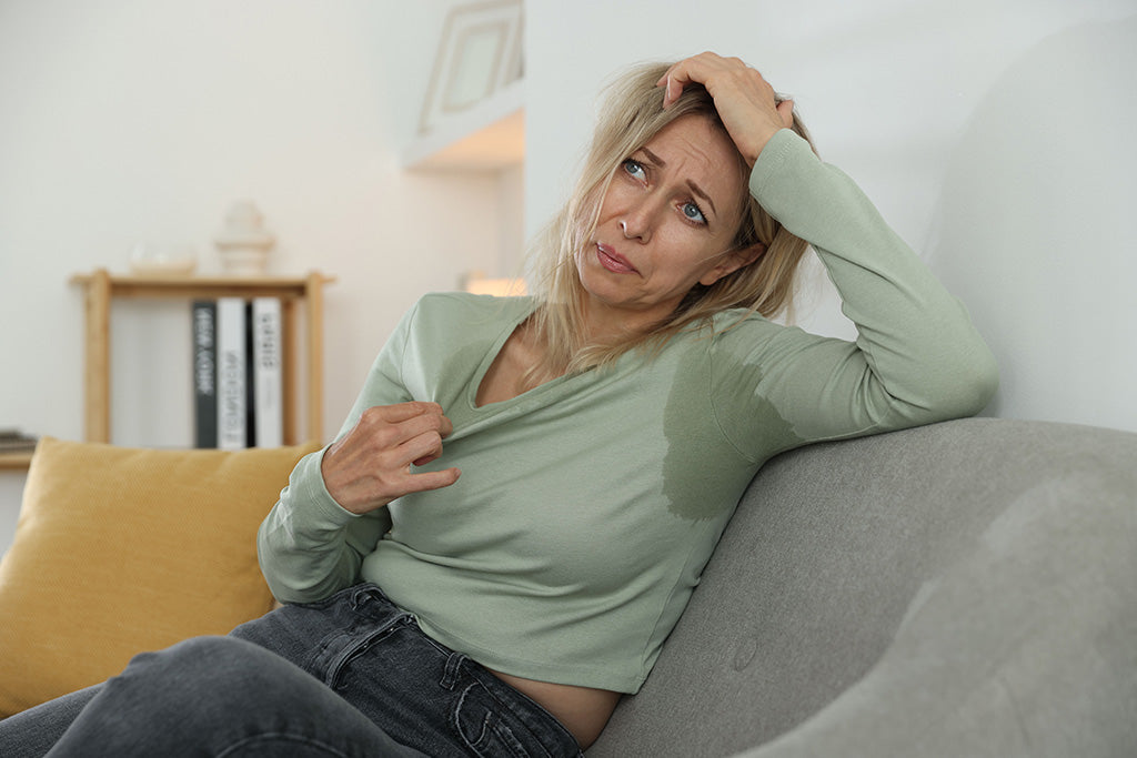 Woman struggling with visible sweat stains on a tight synthetic shirt