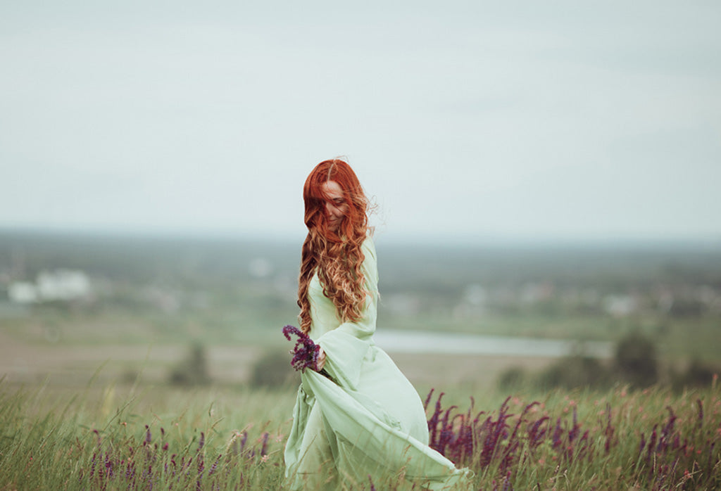 Woman wearing a flowing natural fabric dress in an open meadow