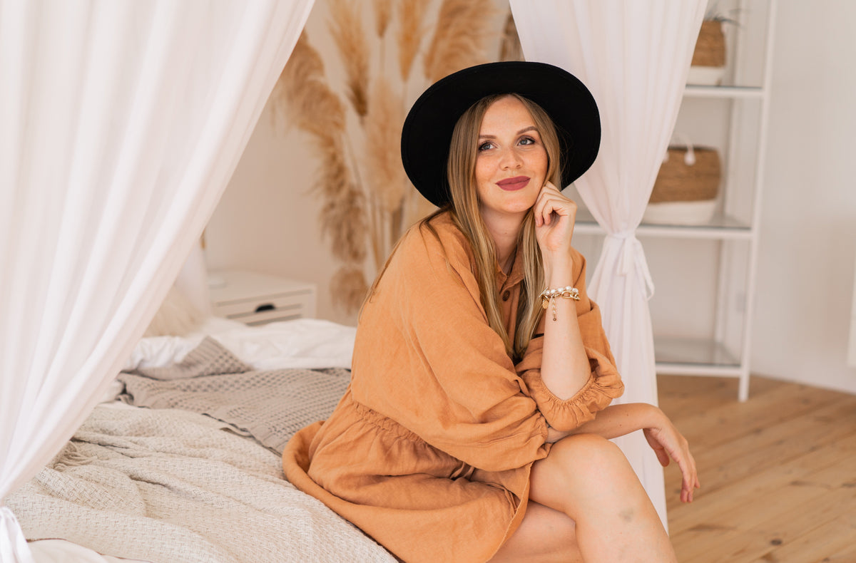 A relaxed woman sitting on a bed in a cozy boho-style room