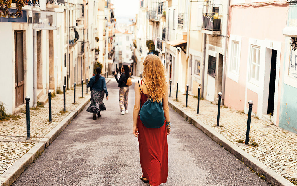 Woman walking down a charming European street wearing a casual summer dress