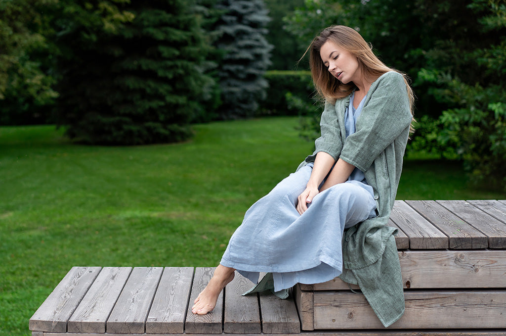 Woman wearing a linen dress sitting outdoors in a green garden