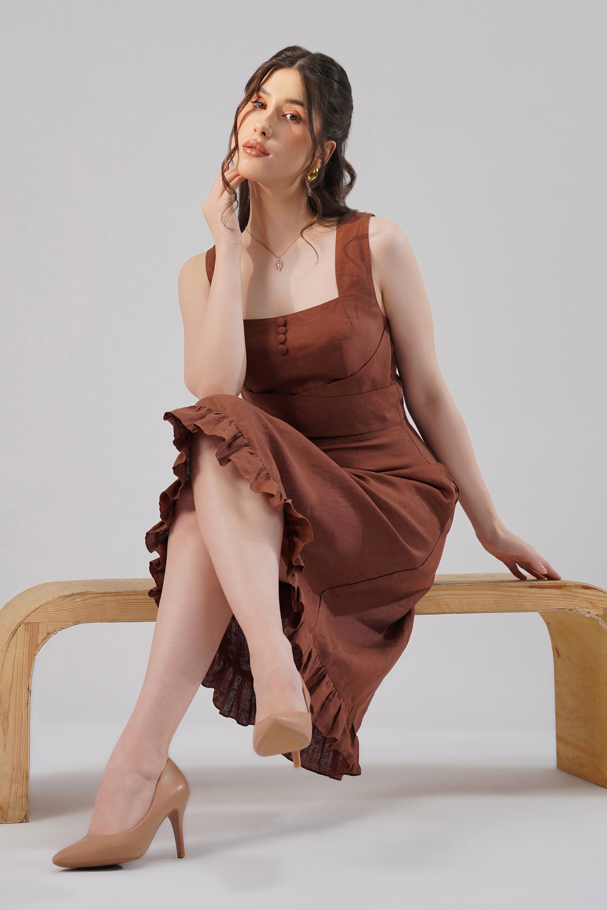 Woman in a european linen dress sitting on a wooden bench