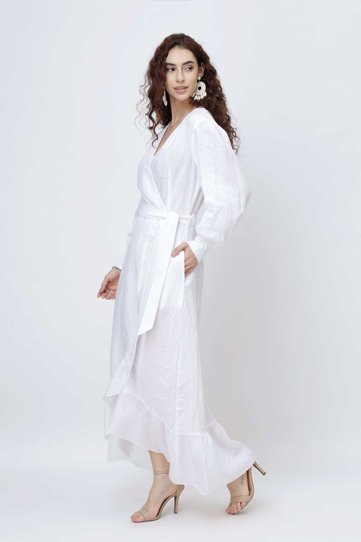 Woman wearing a white linen wrap dress with a belt - side view