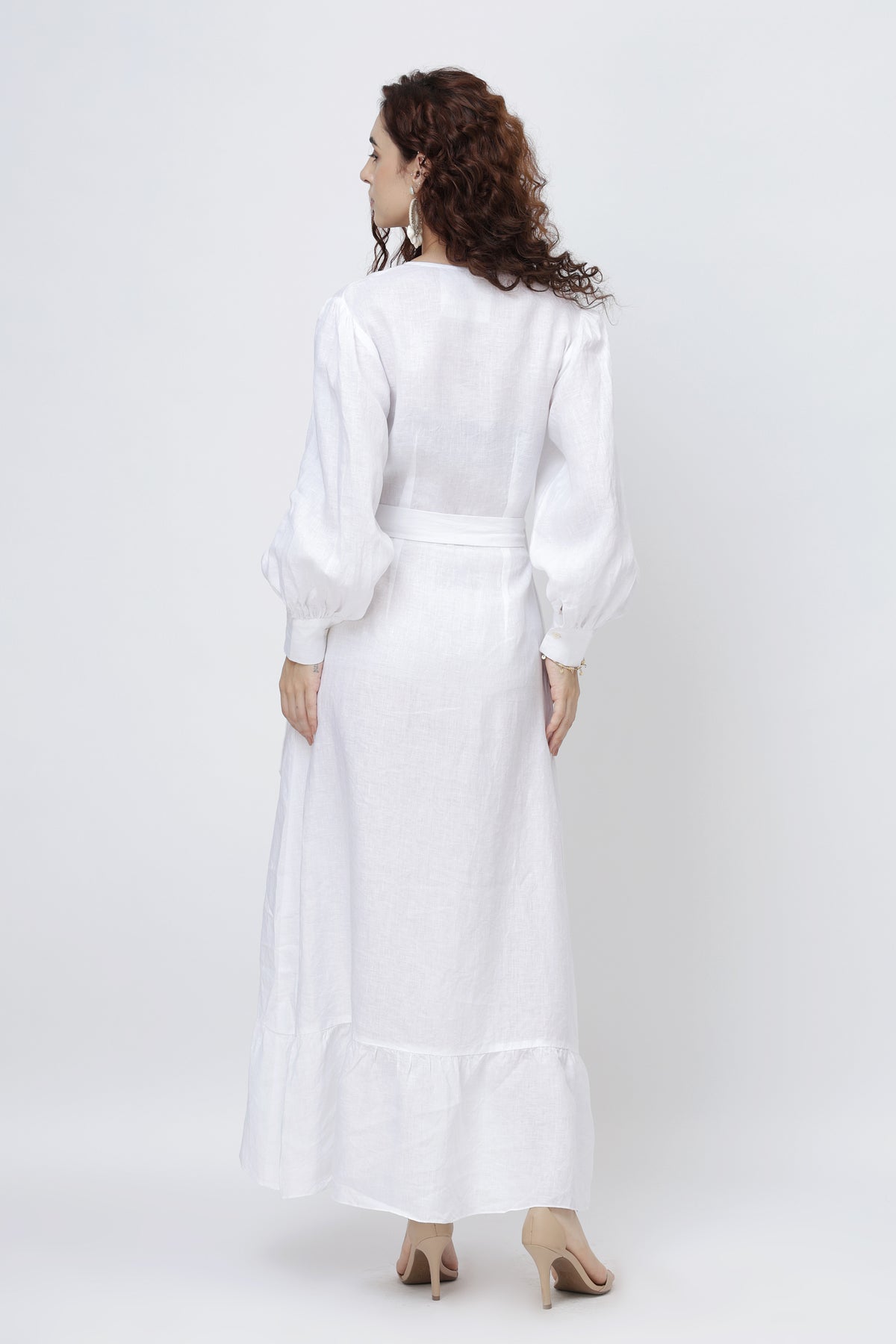 Woman in an optic white European linen dress with long sleeves - back view