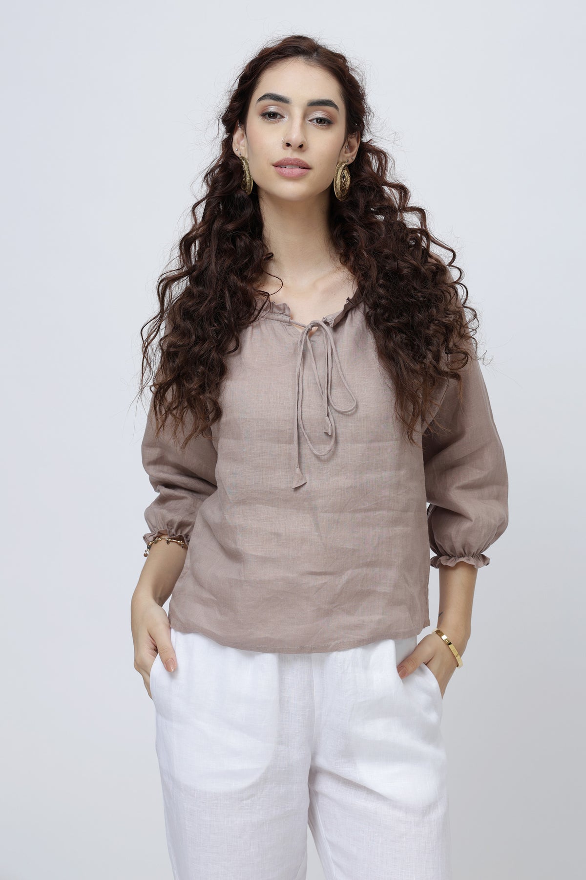 Woman wearing a brown european linen blouse and white pants 