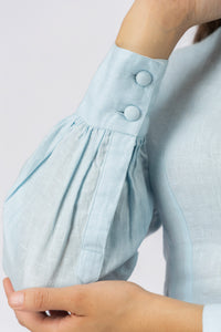Close-up of the bishop sleeve with wide buttoned cuff, covered buttons, and premium linen texture