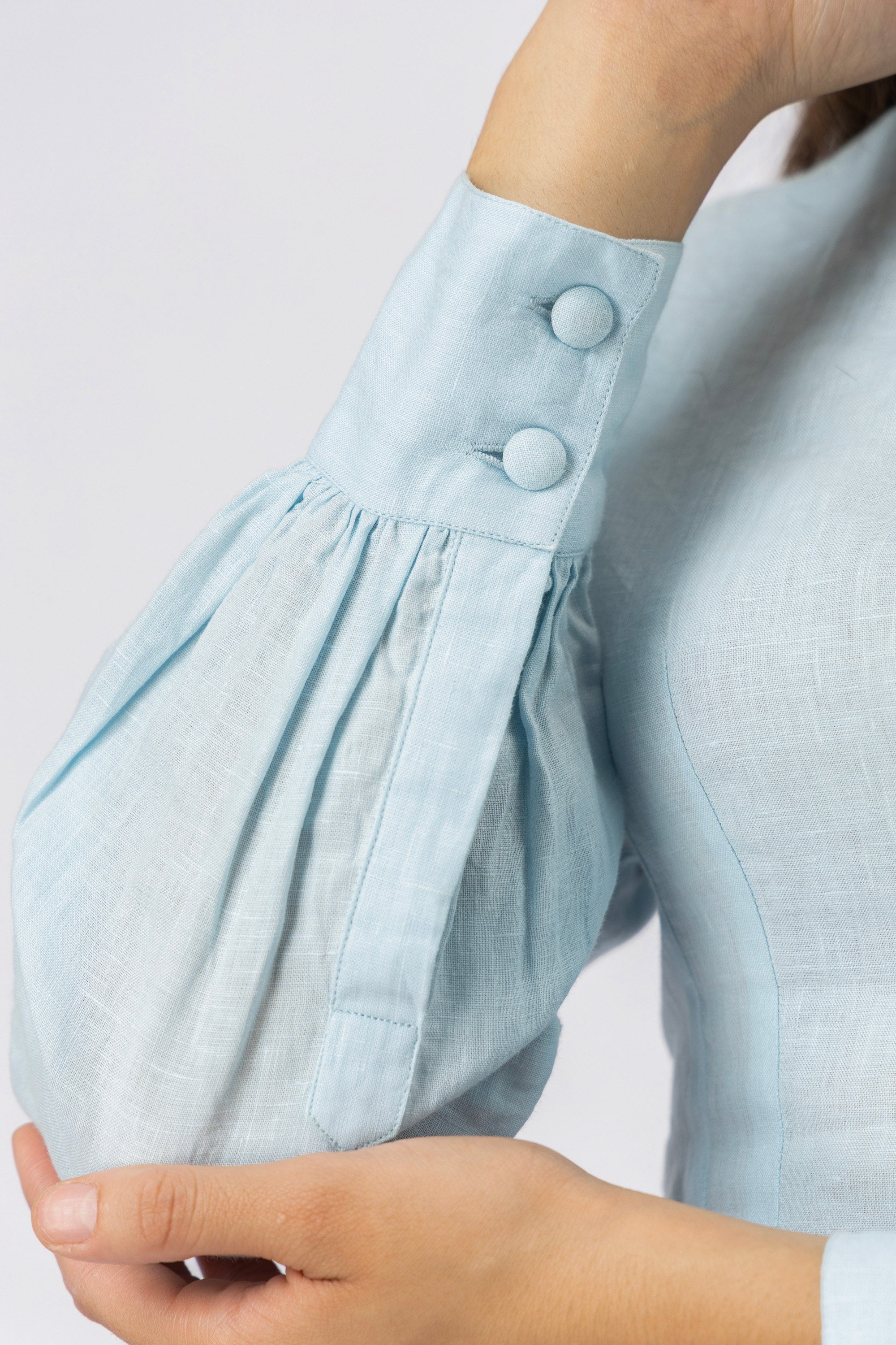 Close-up of the bishop sleeve with wide buttoned cuff, covered buttons, and premium linen texture