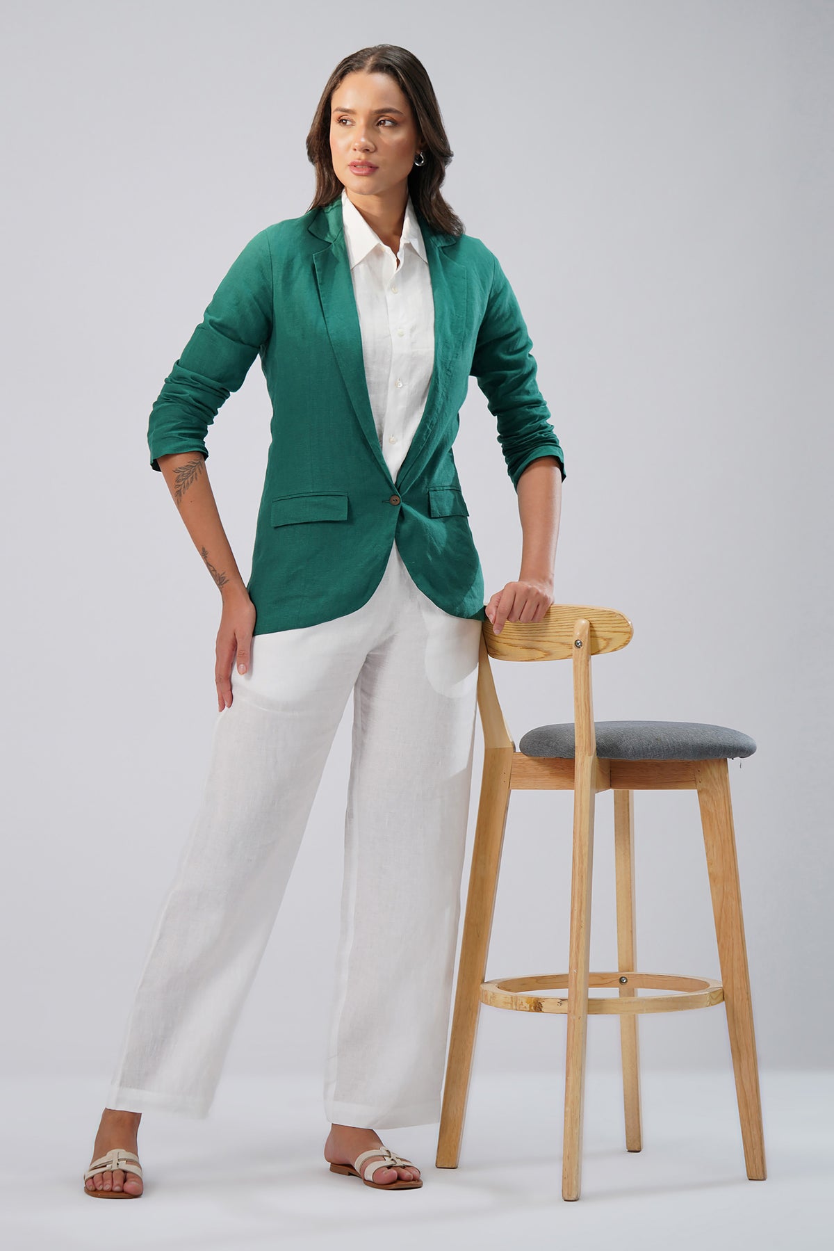 Woman wearing a green linen blazer and white pants 