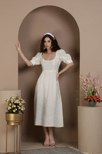 Woman in a European linen midi dress standing in a decorative archway