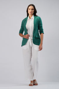 Woman wearing a green linen blazer over a white shirt and pants