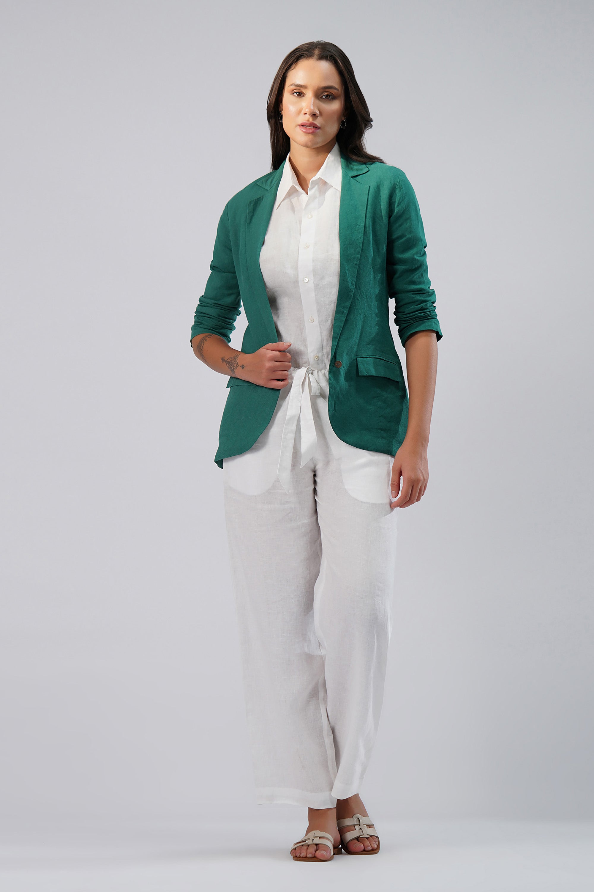 Woman wearing a green linen blazer over a white shirt and pants