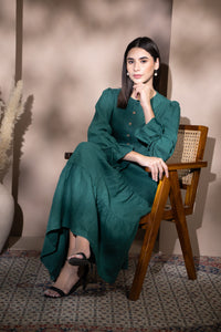 Woman in a tiered linen dress sitting on a wooden chair