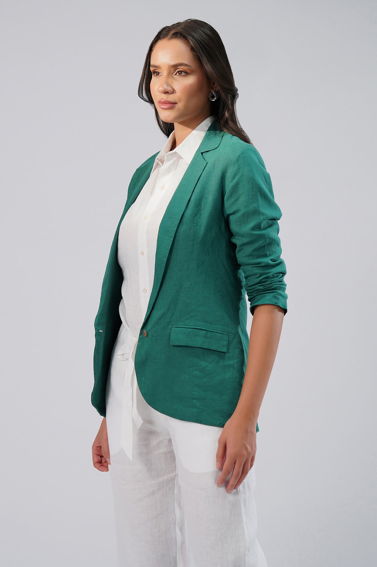 Woman wearing a green european blazer over a white linen shirt and pants