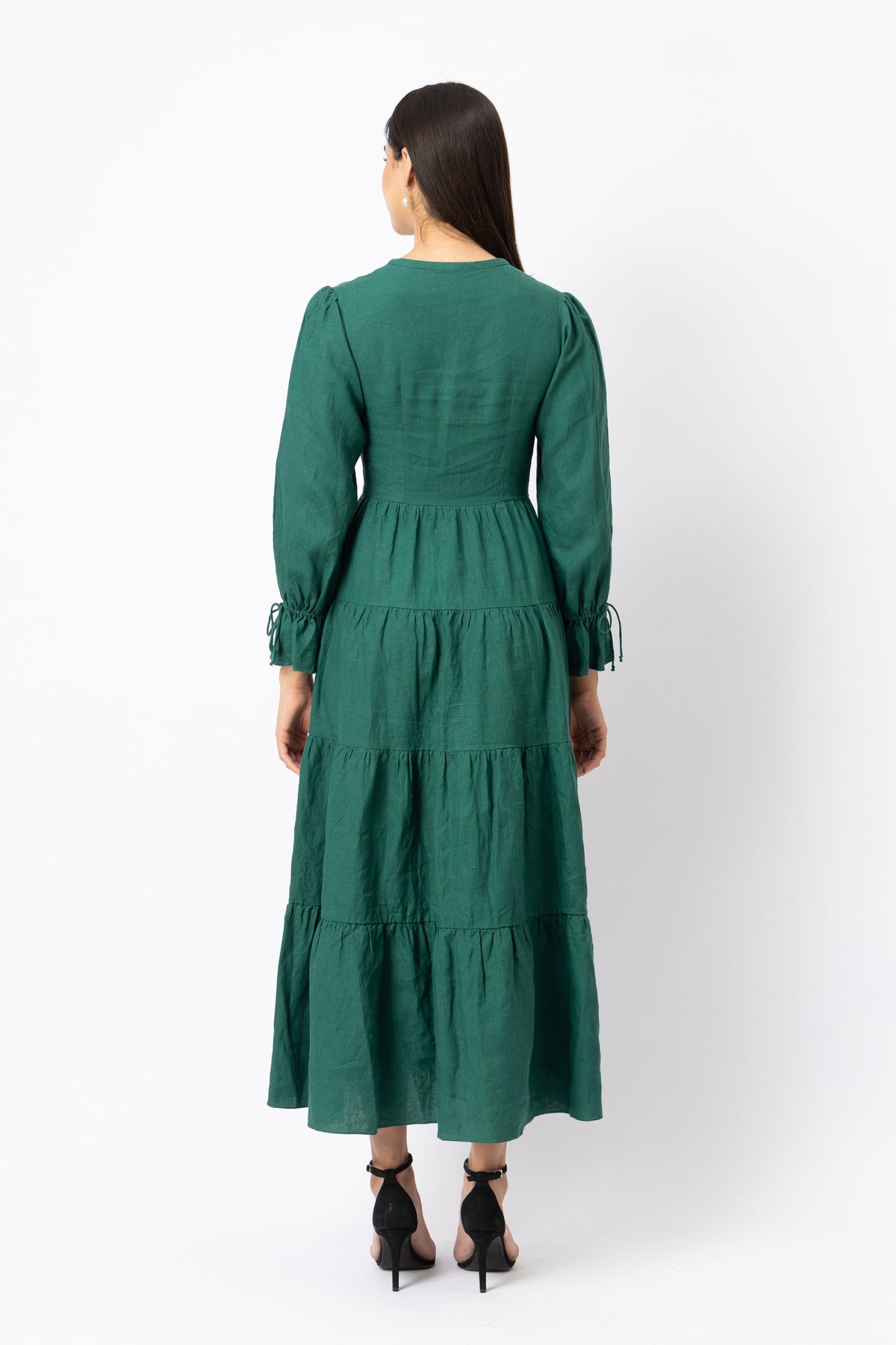 Back view of green linen tiered maxi dress with long sleeves and defined waist