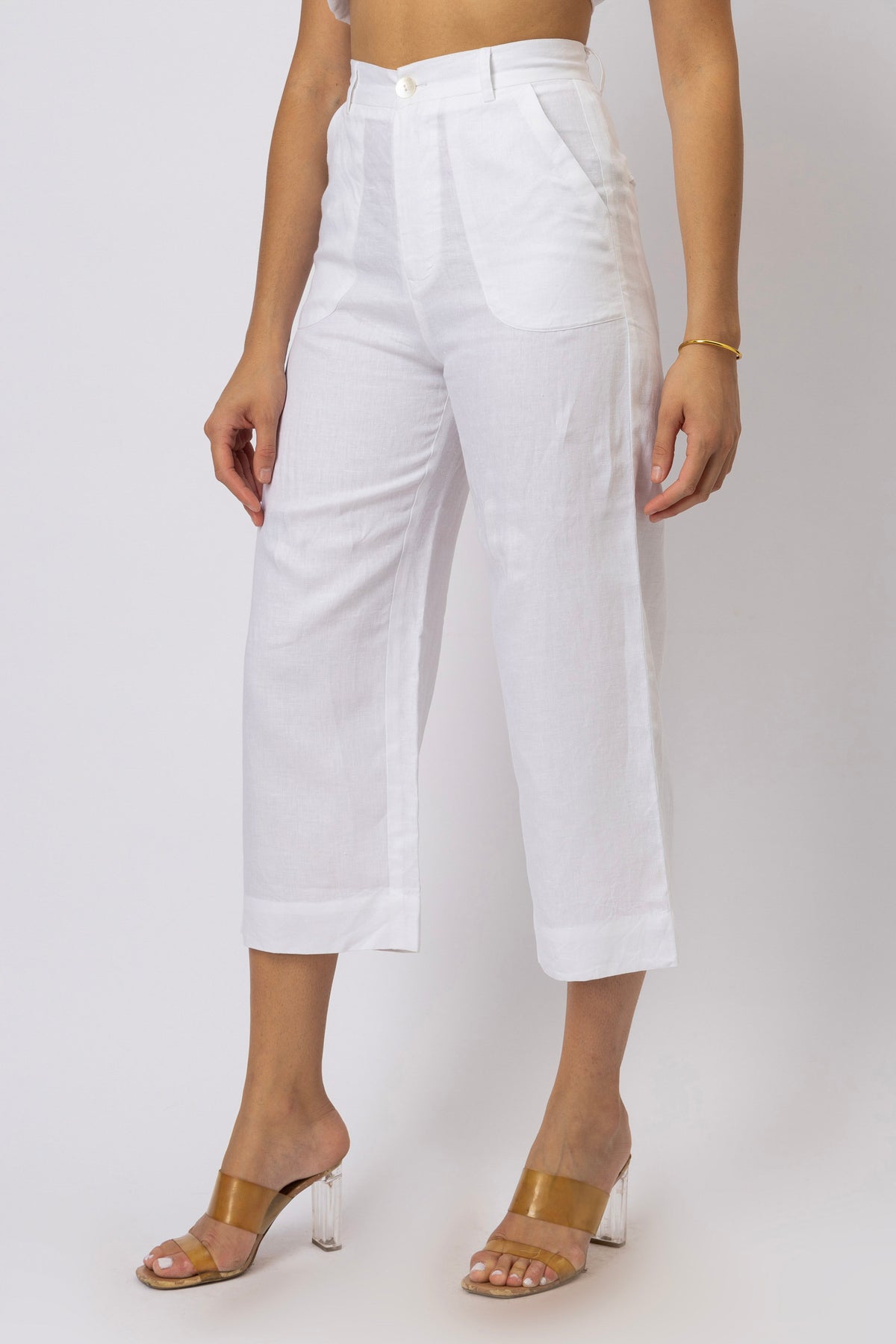 Side-angle view of high-waisted linen capri pants showing the straight-leg silhouette, curved front pocket, waistband, and cropped hem