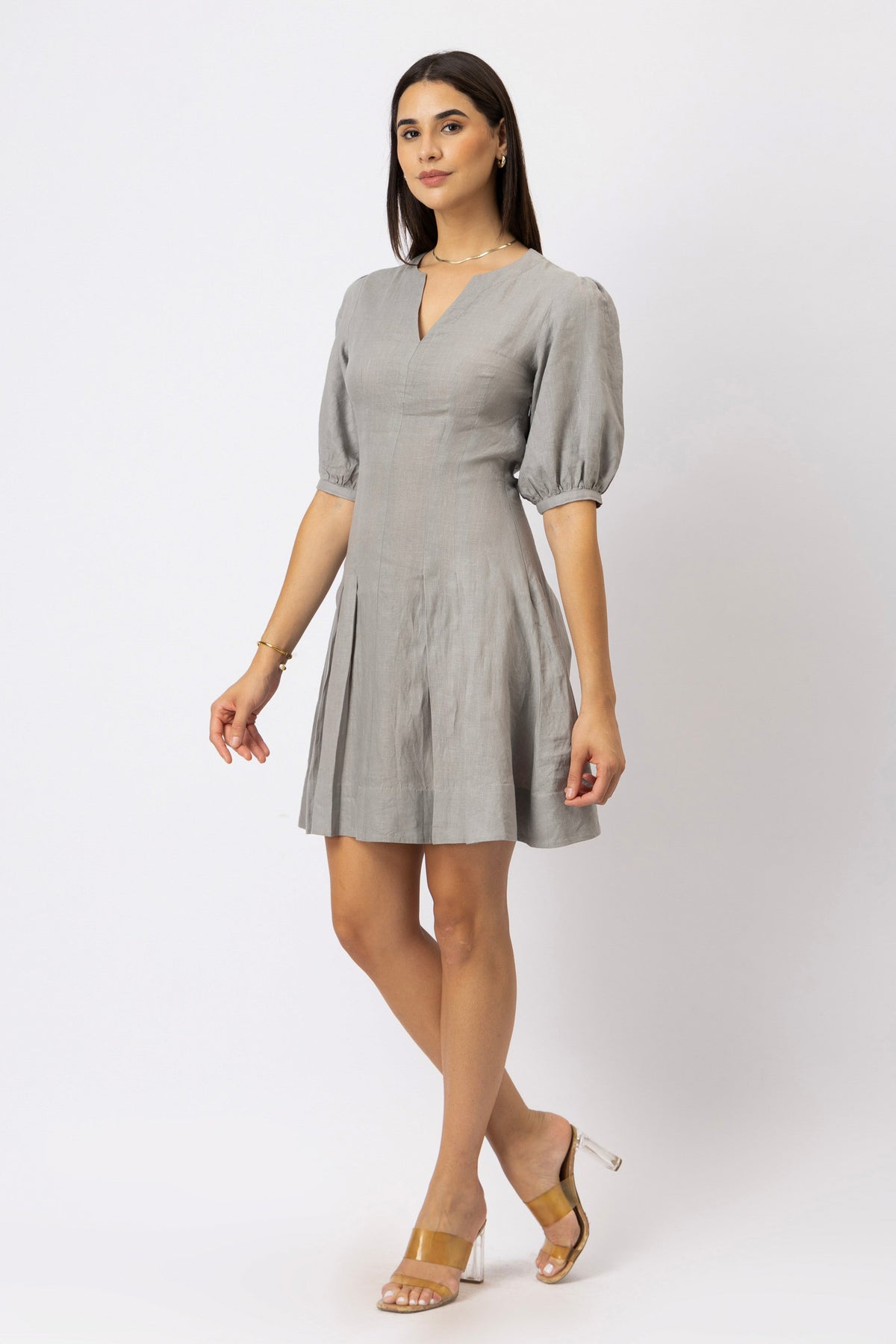 Women's tailored linen fit-and-flare mini dress with puff sleeves and a pleated skirt, shown from a side front angle