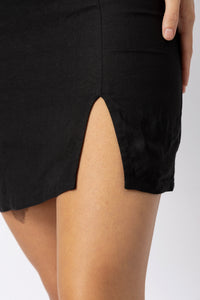 Close-up of a fitted linen mini dress showing the front slit and natural linen texture