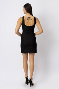 Back view of a fitted linen mini dress featuring an open scoop back and delicate tie-up detail