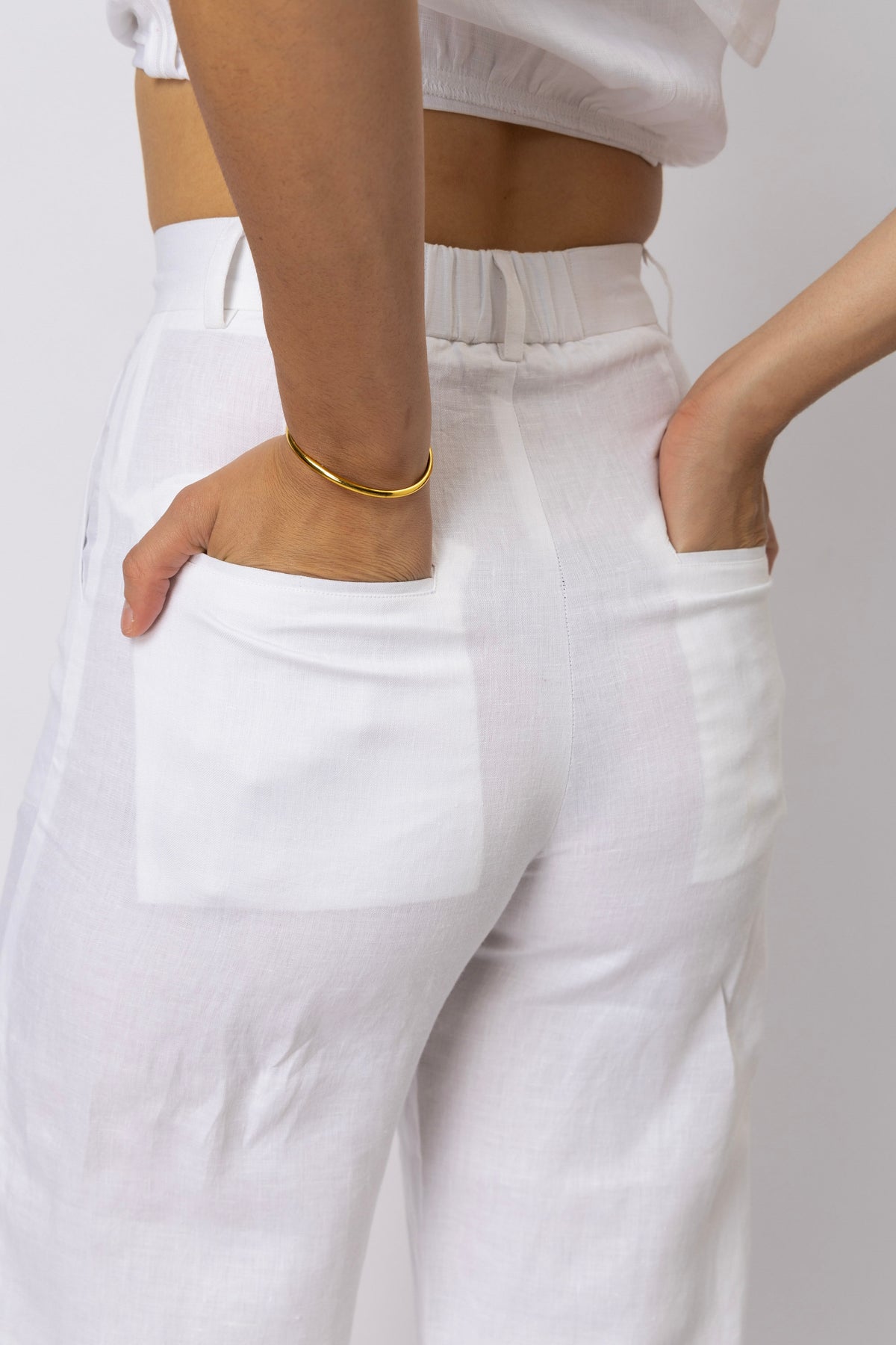 Close-up rear view of linen pants showing the back patch pockets, elasticated waistband, and relaxed straight-leg construction