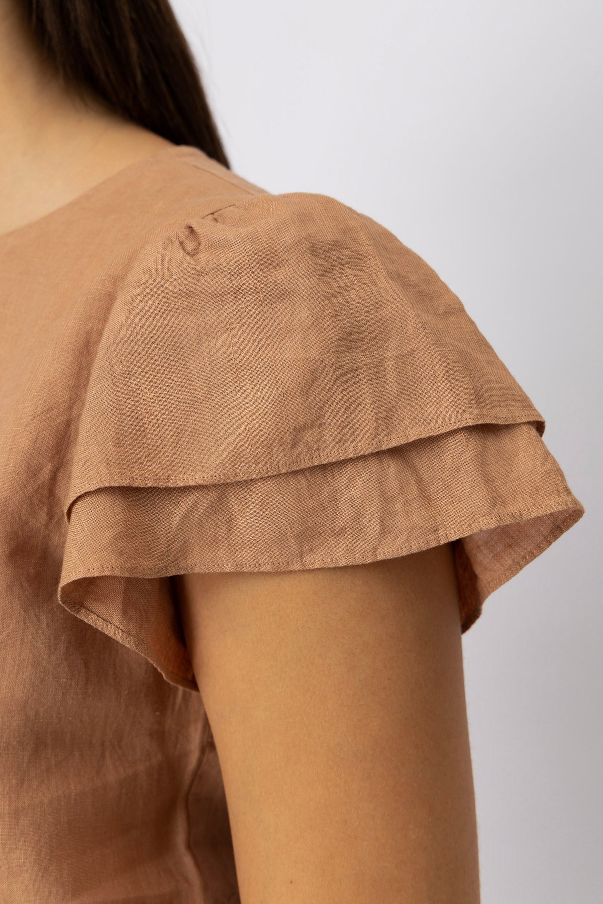 Close-up detail of the double-layer flutter sleeve on a premium linen top