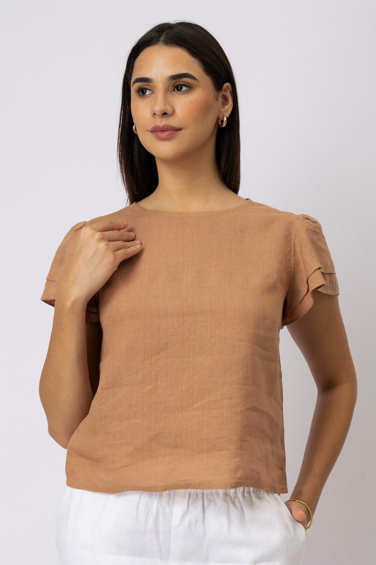 Front view of a woman wearing a linen top with layered flutter sleeves and a round neckline