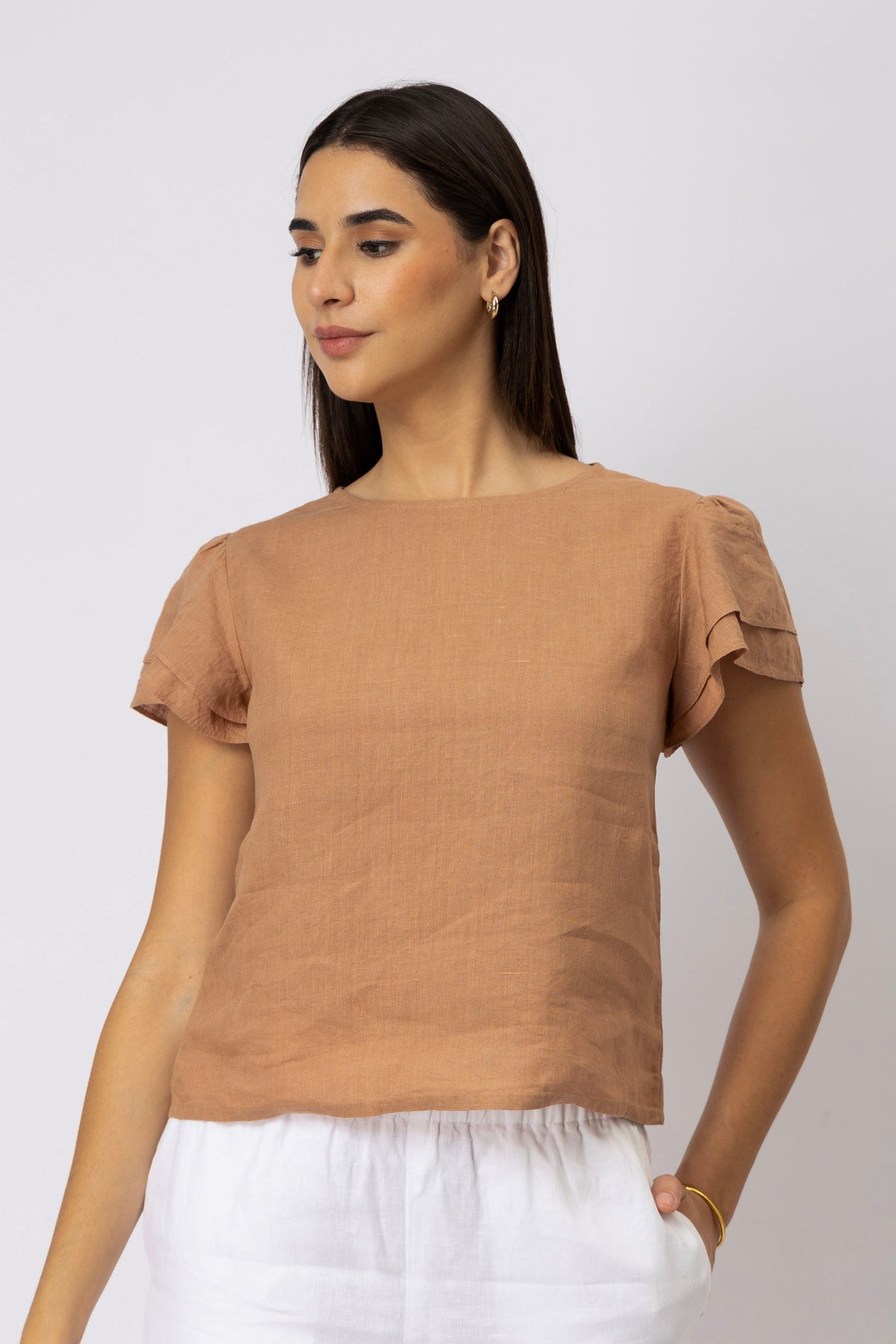 Woman wearing a linen top with layered flutter sleeves and round neckline