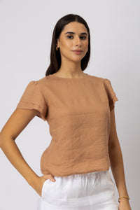 Three-quarter view of a woman wearing a linen top with layered flutter sleeves and a round neckline