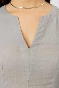 Close-up of the V-neckline on a tailored women's linen mini dress, highlighting the clean finish and natural linen texture