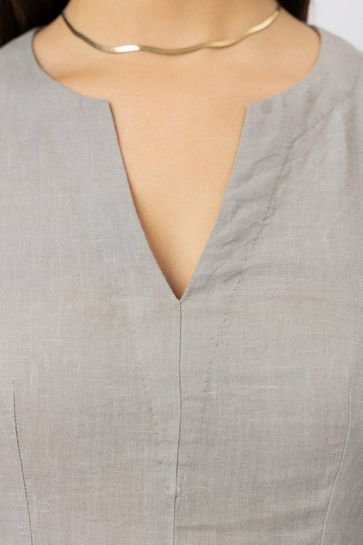 Close-up of the V-neckline on a tailored women's linen mini dress, highlighting the clean finish and natural linen texture
