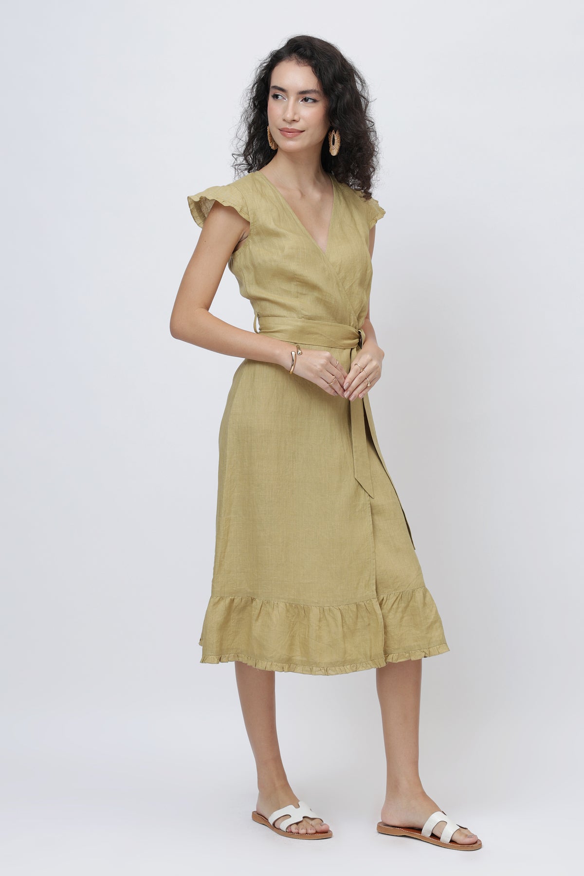 Woman wearing a khaki European linen dress with ruffled sleeves and hem