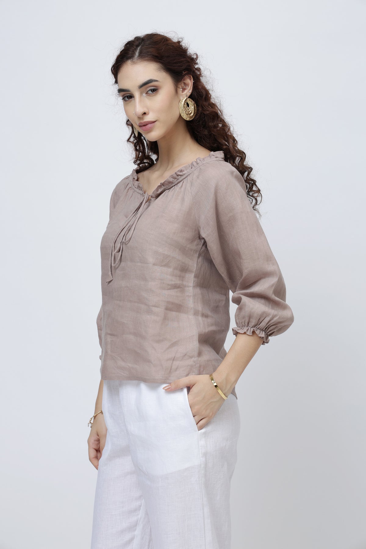 Woman wearing a brown linen blouse and white pants