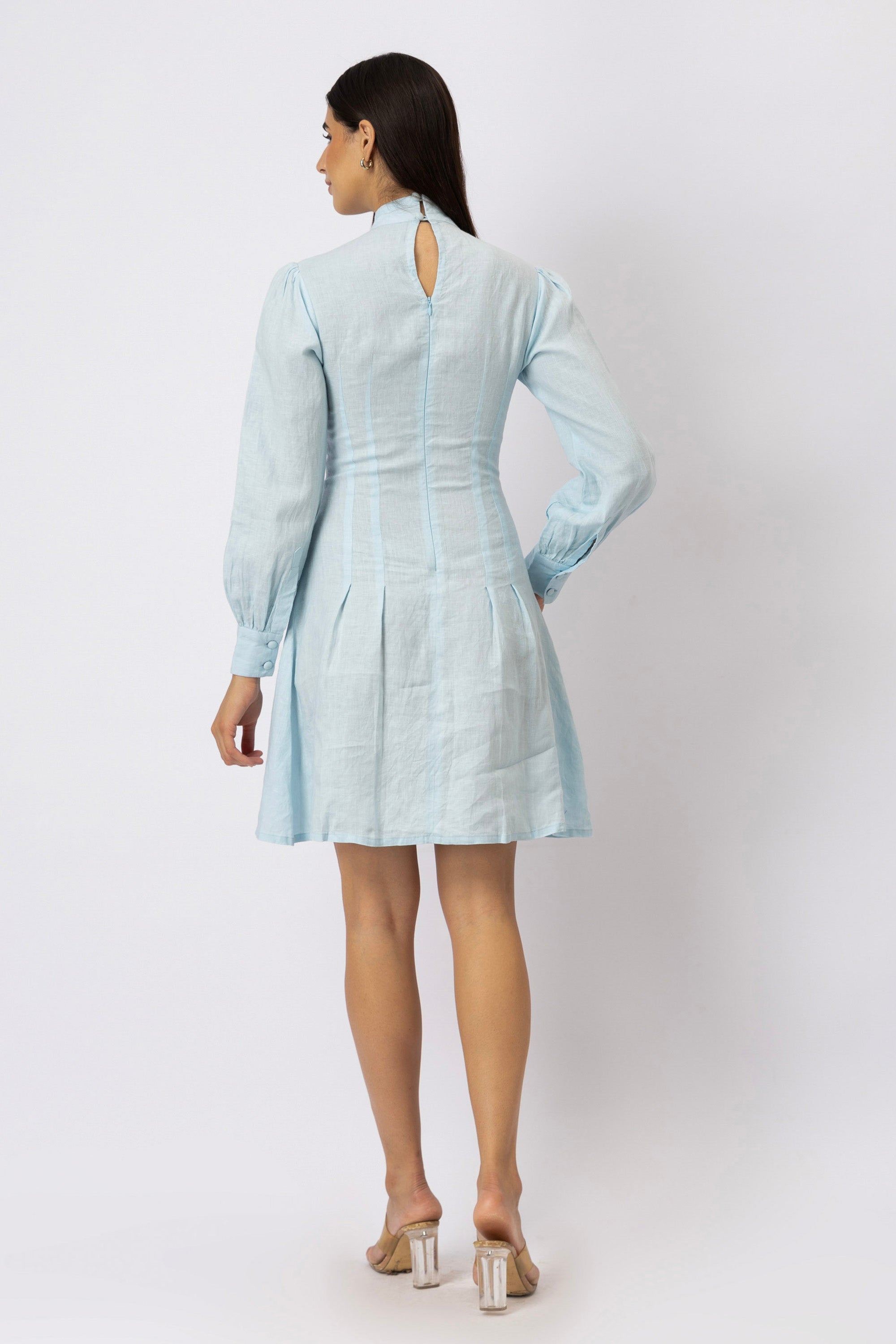 Back view of a mock neck pleated linen mini dress featuring a keyhole neckline, concealed back zipper