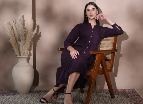 Woman in a dark purple linen dress sitting on a wooden chair