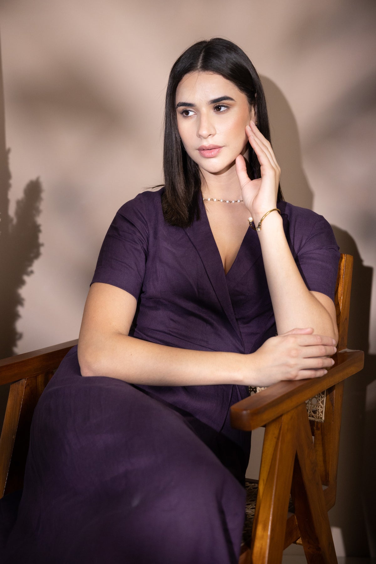 Woman in a purple linen dress sitting on a wooden chair