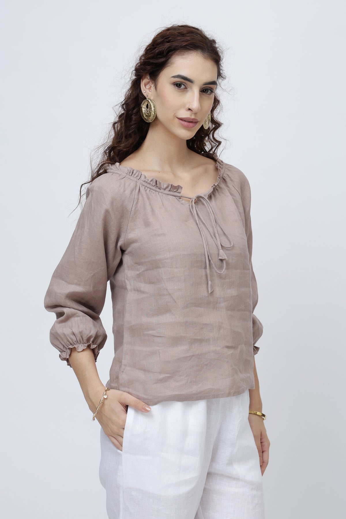 Woman wearing a beige linen blouse with a tie neckline 