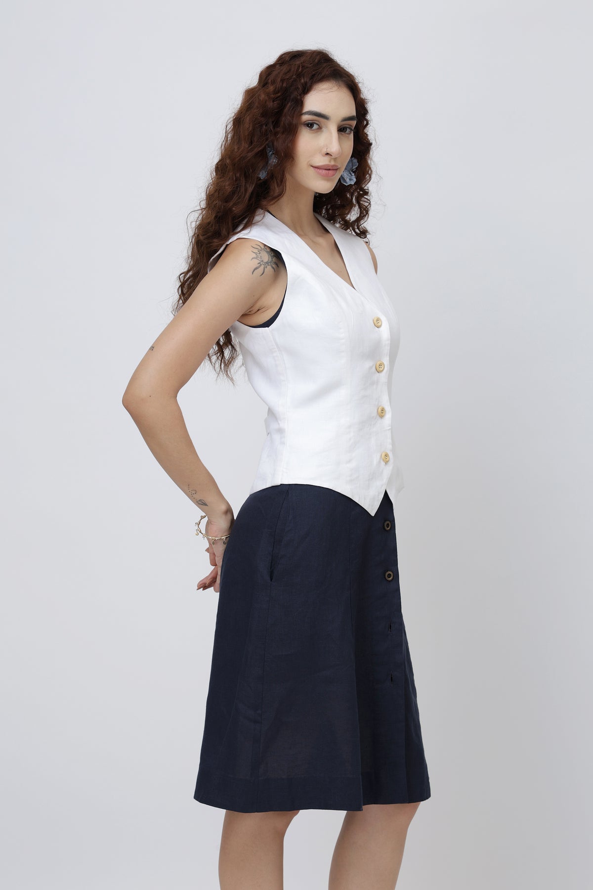 Woman wearing a European linen vest with wooden buttons and a navy skirt