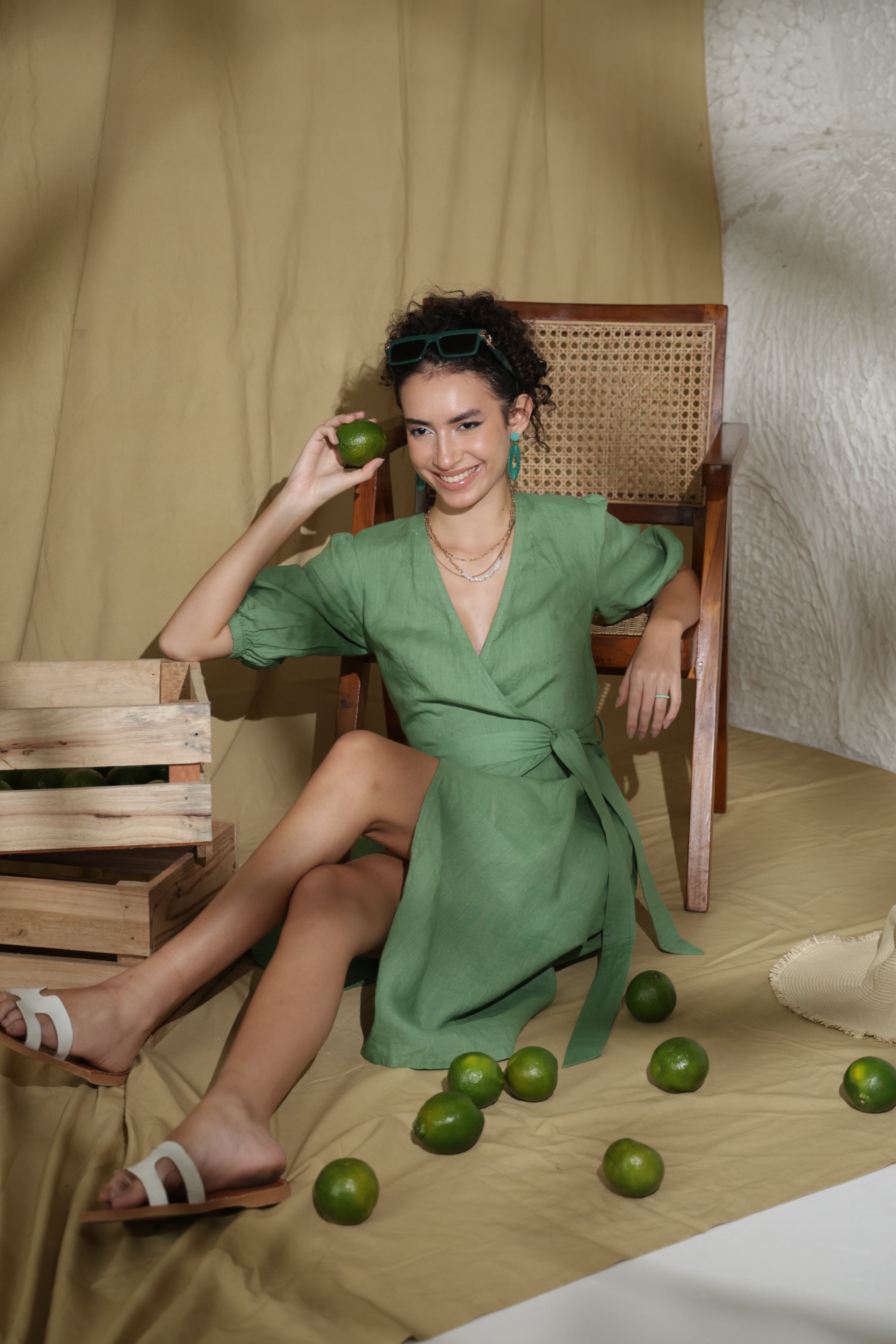 Woman in green linen dress sitting on the floor with limes around her