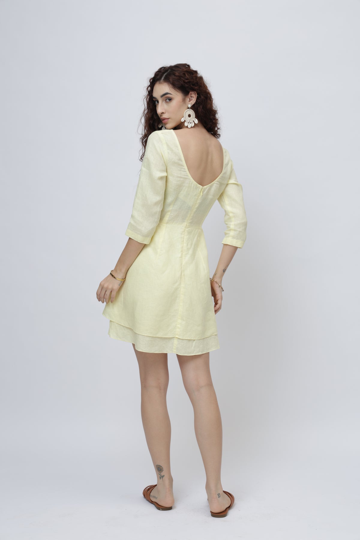 Woman wearing a light yellow linen dress with a deep back design