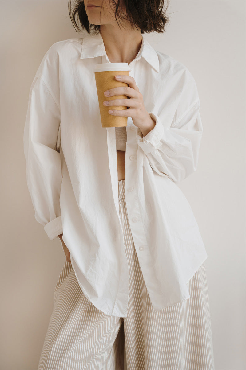 young women wearing linen shirt with coffee in hand